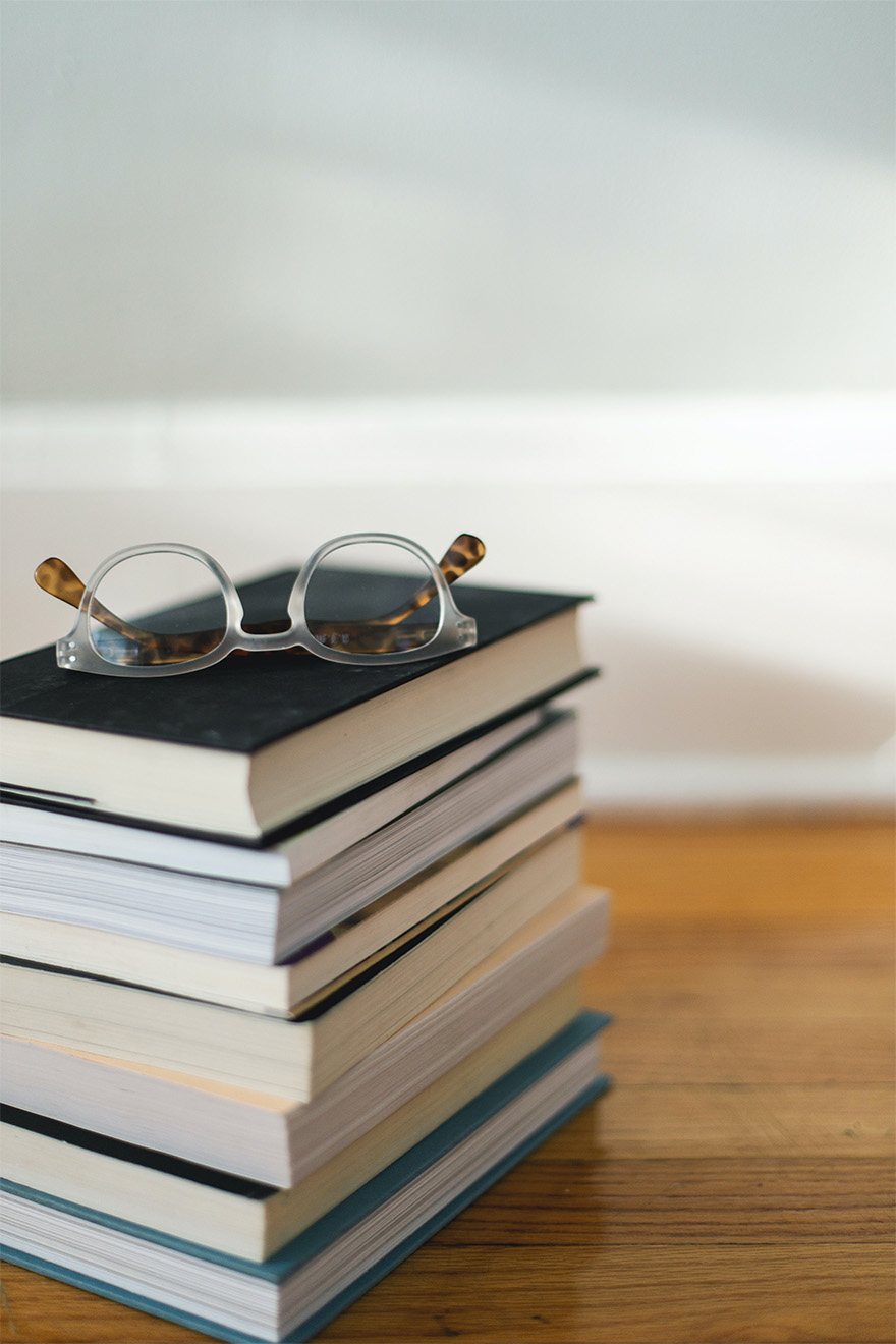 pile of books with glassses on top