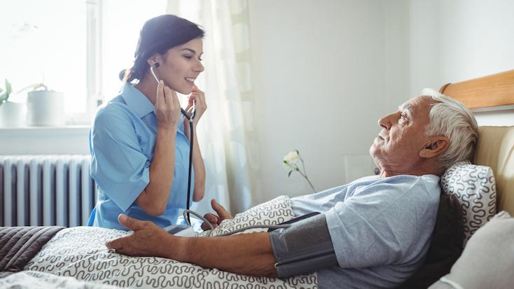 nurse caring for an elderly man lying in bed